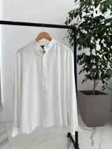 Camisa oversize de lino color blanco, con cuello mao, manga larga y cierre frontal de botones.