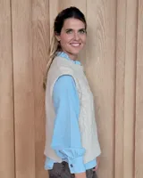 Chaleco de punto gris oscuro con diseño de trenzas y rombos en relieve, cuello redondo y terminaciones acanaladas.