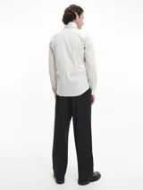 Camisa de manga larga color blanco hueso, de corte slim, con cuello tradicional y cierre frontal de botones.