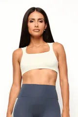 Top deportivo de entrenamiento con escote redondeado y espalda tipo nadador, confeccionado en poliamida tecnológica de alto rendimiento. Cuenta con forro interno y abertura para colocar almohadillas.