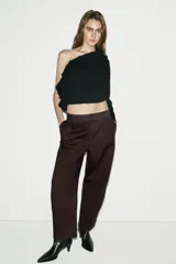 Pantalón de tiro alto con pinzas delanteras, diseño de pierna holgada tipo balloon que se estrecha hacia el tobillo. Cuenta con bolsillos frontales, bolsillos de plastrón en la parte trasera y cierre frontal con cremallera y botón.