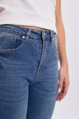 Pantalón jean cropped flare de color azul medio, corte recto ligeramente acampanado en la parte inferior y tiro medio.