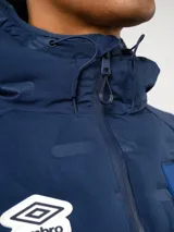 Campera Umbro del Club Nacional de Football, modelo Alpine. Diseño en color azul marino con frente acolchado termosellado, mangas y espalda de tejido polar, capucha integrada y cierre frontal completo. Incluye logo de Umbro y escudo del club en el pecho.