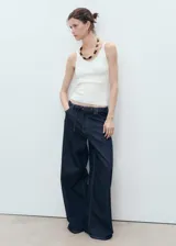 Top de punto fino con cuello en pico y tirantes finos, de diseño entallado y corte corto.