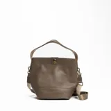 Cartera tipo bucket de cuero sintético color beige, con correa de hombro ajustable y cierre con broche metálico.