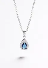 Collar de cadena fina de plata 925 con dije en forma de gota con piedra central azul rodeada de pequeñas circonias brillantes.