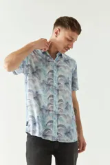 Camisa de hombre estampada con diseño de hojas de palmera en tonos celeste, azul y gris. Corte slim fit, manga corta, cartera abotonada y logo bordado.
