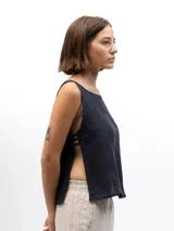 Musculosa de lino con cuello redondo y laterales abiertos unidos por tres tiras horizontales. Presenta un diseño holgado y fresco, ideal para uso casual.
