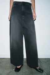 Jeans de tiro bajo con corte baggy y pierna ancha. Presenta diseño de cinco bolsillos, cierre frontal con cremallera y botón metálico, y cintura con trabillas para cinturón.