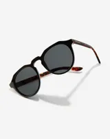 Lentes de sol Hawkers unisex, modelo Warwick, con montura redonda negra y patillas Carey.