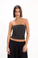 Top strapless negro de corte ajustado, con diseño estampado de pequeños círculos y rombos dorados y plateados.
