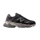 Championes urbanos New Balance modelo 9060, con diseño robusto y moderno en tonos negro y gris. Presentan una combinación de materiales en gamuza y malla, con el logo N característico en los laterales y una suela voluminosa con tecnología de amortiguación.