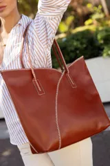 Bolso tote de cuero color marrón con costuras blancas a contraste. Tiene doble asa de hombro y diseño minimalista.