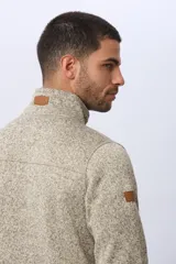 Campera texturada con interior en polar, color tostado jaspeado, cuello alto y cierre frontal con cremallera.