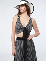 Top corto de satén a rayas verticales blancas y negras, con escote en V y nudo en la parte delantera.