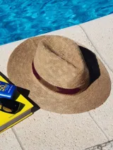 Sombrero de paja color beige con cinta marrón alrededor de la copa.