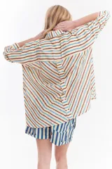 Camisa oversize de algodón con estampado de rayas multicolor en distintas direcciones, cuello camisero, mangas largas y detalle de botonera vertical en la espalda.