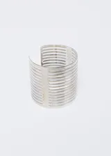 Brazalete plateado rígido, con diseño de franjas horizontales caladas.