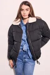 Campera puffer negra con cuello de corderito color crema, cierre frontal con cremallera y cordón ajustable en el ruedo.
