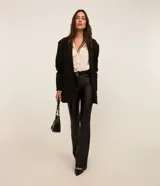 Pantalón bootcut Cortelle de sarga resinada color negro, con cintura mediana, bolsillos delanteros y traseros, cierre con botón y cremallera, y trabillas en la cintura.