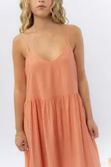 Vestido midi de corte amplio con breteles finos y escote en V. Confeccionado en gasa de algodón con textura, presenta un diseño escalonado con vuelo en el ruedo.