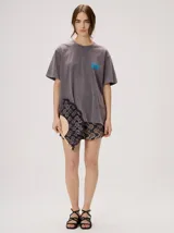 Remera oversize de corte cuadrado, color lila con efecto acid wash, cuello redondo y pequeño gráfico frontal en color rojo.
