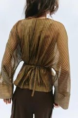 Camisa marrón a rayas con cuello redondo, mangas largas anchas y puños rectos. Cuenta con cierre frontal de botones y un lazo cinturón ajustable del mismo tejido en la cintura.