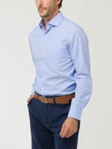 Camisa de manga larga de popelina de algodón en color celeste, con cuello italiano, cierre frontal de botones y un bolsillo en el pecho con el logo bordado de la marca.