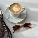 Lentes de sol con marco metálico de diseño ovalado y cristales oscuros. Presentan un estilo moderno y minimalista con patillas finas.