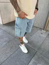 Bermuda de jean estilo cargo con bolsillos laterales y corte holgado. Presenta un lavado claro y costuras reforzadas.
