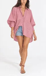 Camisa oversize de lino, color blanco, de corte asimétrico con cuello camisero, bolsillos plaque al frente y mangas abullonadas.
