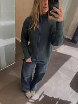 Campera tejida con textura vanizada a rayas verticales en color lila y negro, con cierre frontal y cuello alto.