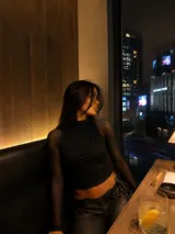 Blusa negra de cuello alto con cuerpo central opaco y mangas largas de tul transparente. Presenta un diseño ajustado con frunces en la parte frontal.