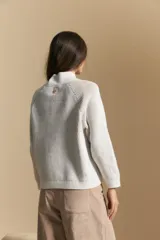Polera de tejido acanalado en color marrón con detalles de líneas en tono lila, cuello alto y mangas largas con diseño raglán.