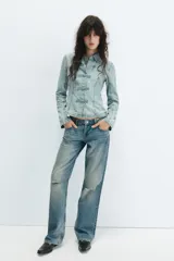 Camisa de denim celeste con cuello solapa, manga larga y cierre frontal con nudos de tela.
