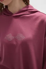 Canguro con capucha de calce holgado, color bordó, con detalle de aplique de strass en el pecho.