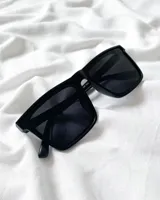 Lentes de sol con armazón negro cuadrado y cristales oscuros.