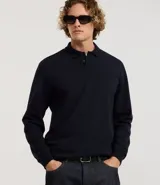 Buzo de algodón color azul marino, de manga larga y cuello polo con botones. Presenta puños y bajo ajustados.