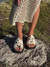 Sandalias tipo ojotas con base negra y tira ancha de pelo sintético con estampado animal print de vaca.