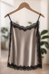 Musculosa tipo lencero de satén color champagne con detalles de encaje negro en el escote, laterales y ruedo. Posee breteles finos ajustables.