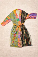 Bata tipo kimono de diseño patchwork, confeccionada con una mezcla de telas estampadas con motivos florales, paisley y geométricos en tonos verdes, naranjas y violetas. Presenta mangas tres cuartos, aberturas laterales en el ruedo y un lazo ajustable en la cintura.