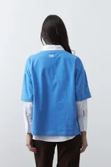 Remera de manga corta con corte boxy fit, color blanco, con estampa frontal geométrica en tonos azul, rosado y marrón.