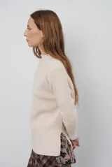 Polera de tejido de punto en color beige, con cuello alto y mangas largas con puños acanalados.