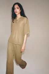 Pantalón de pierna recta color tostado, con tiro medio y cintura elástica. Confeccionado en hilatura con mezcla de viscosa.