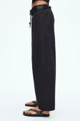 Pantalón cargo de corte holgado en color marrón, confeccionado en mezcla de algodón y nailon. Presenta cintura elástica de talle alto y perneras estilo globo con bolsillos tipo parche a los lados y costuras visibles en la parte delantera.