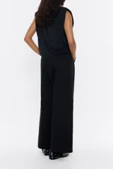 Pantalón de vestir color marrón claro, de corte ancho, con pinzas en la parte delantera, bolsillos laterales y trabillas en la cintura.