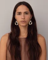 Par de aros colgantes de bronce y alpaca color plateado, con forma orgánica irregular y textura martillada. Cierre con perno y mariposa de plata 925.