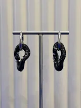 Aros colgantes de diseño orgánico en color negro con incrustaciones de vidrio brillante, montados sobre argollas de plata 925.