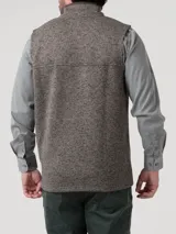 Chaleco de hombre de tejido tipo tweed o jaspeado en tonos grises y verdes, con cuello alto y cierre frontal completo. Presenta bolsillos laterales con ribete oscuro.