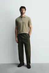 Polo de punto negro, manga corta, con cuello solapa y cierre frontal de tres botones. Presenta un calce regular y acabados en rib en mangas y ruedo.